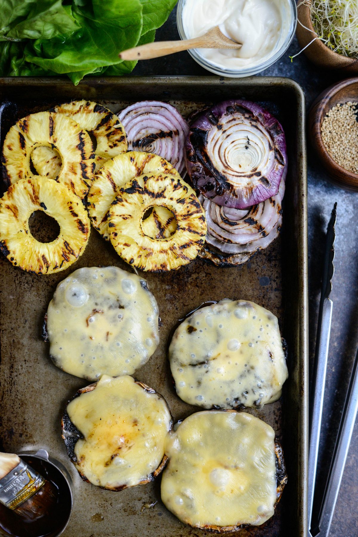 teriyaki portobello burgers, grilled pineapple and red onion on a sheet pan.