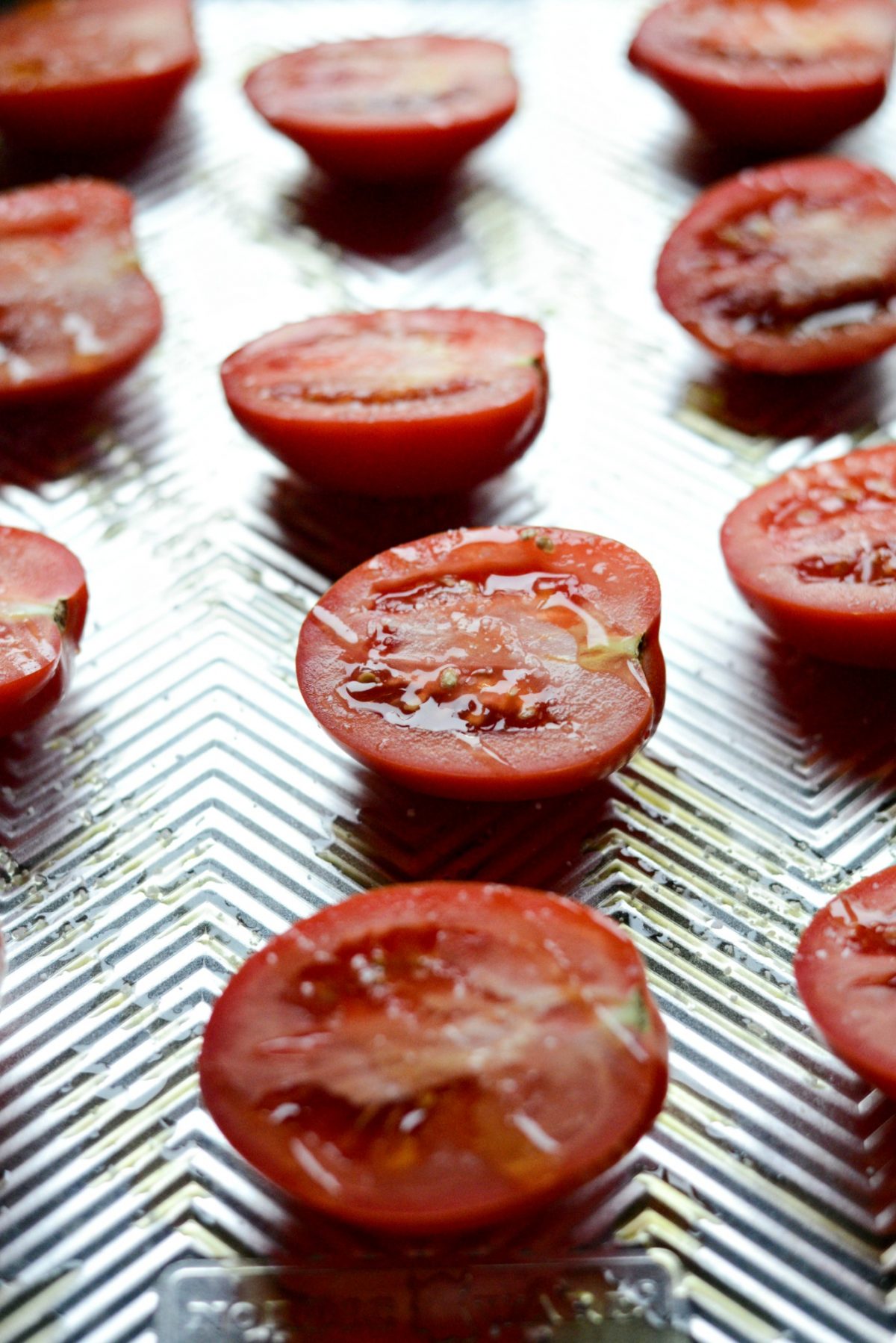 tomatoes with olive oil on a rimmed sheet pan.