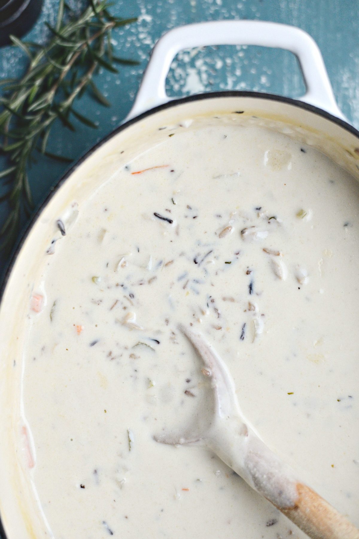 creamy turkey wild rice soup in white pot with wooden spoon.