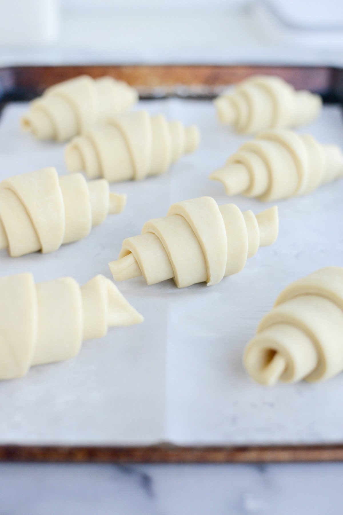 rolled croissants on lined rimmed baking sheet