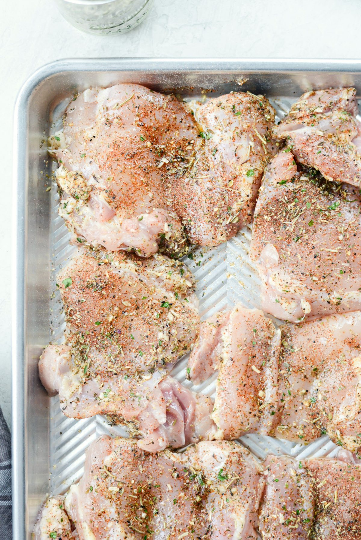 seasoned chicken thighs on a rimmed baking sheet