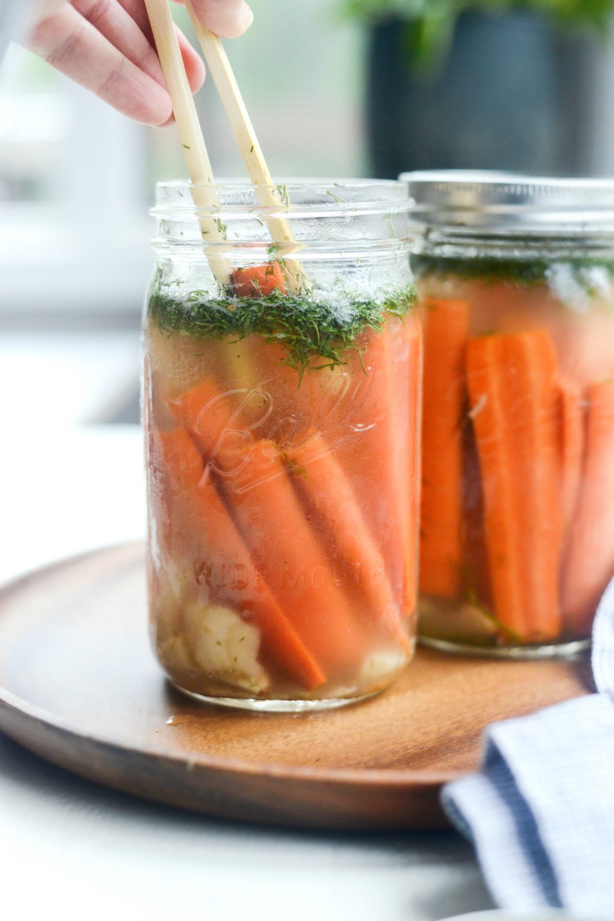 using bamboo tongs to remove Naturally Fermented Dilly Carrots from jar