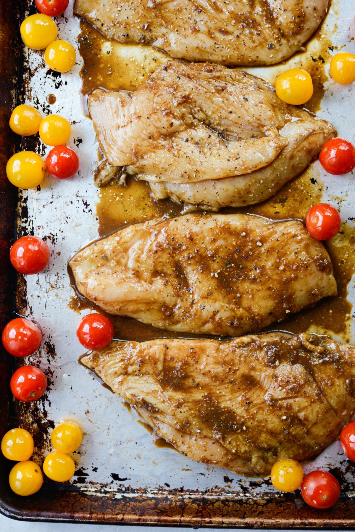 add chicken and tomatoes to a sheet pan sprayed with olive oil