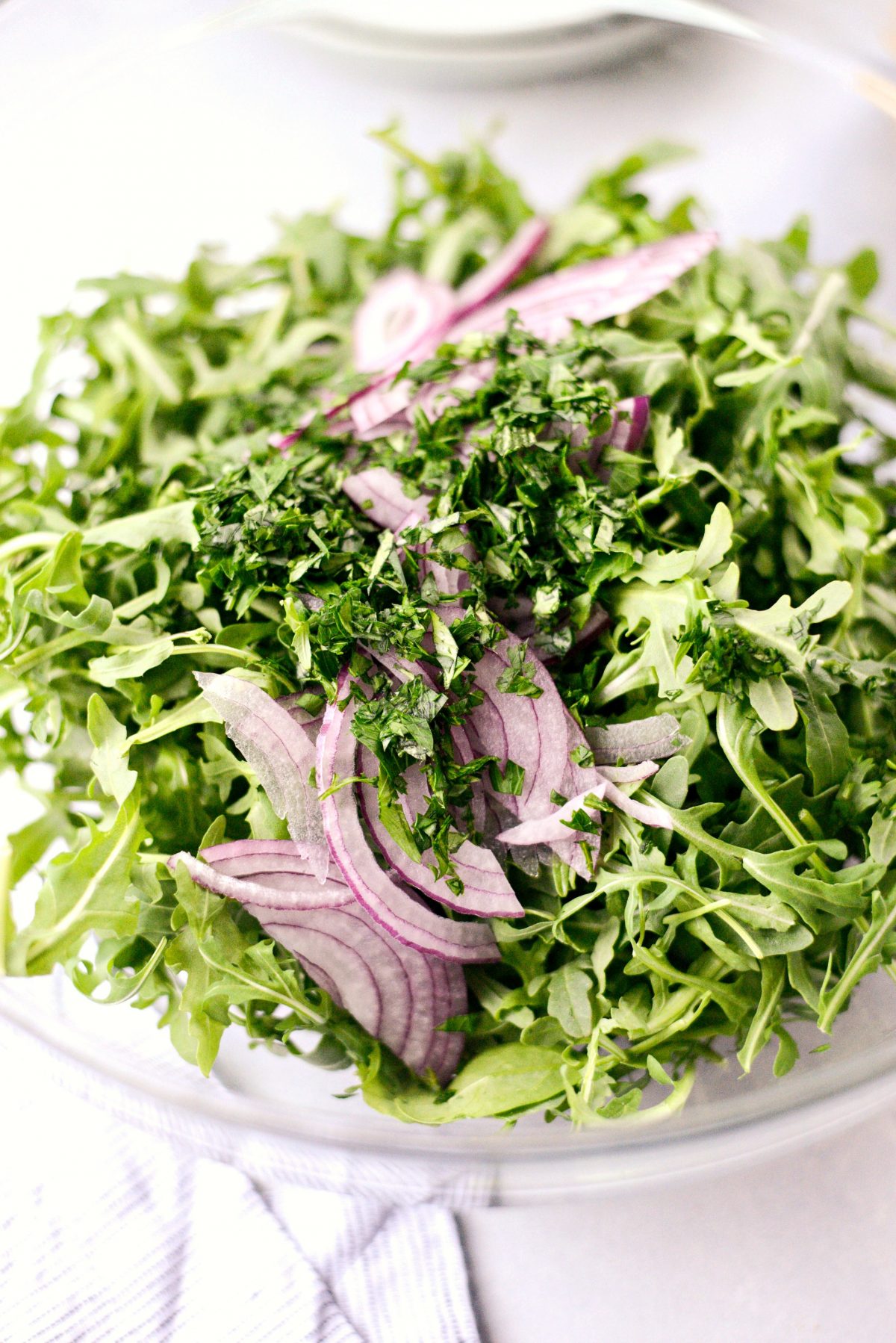 arugula, red onion and chopped cilantro and parsley in a bowl