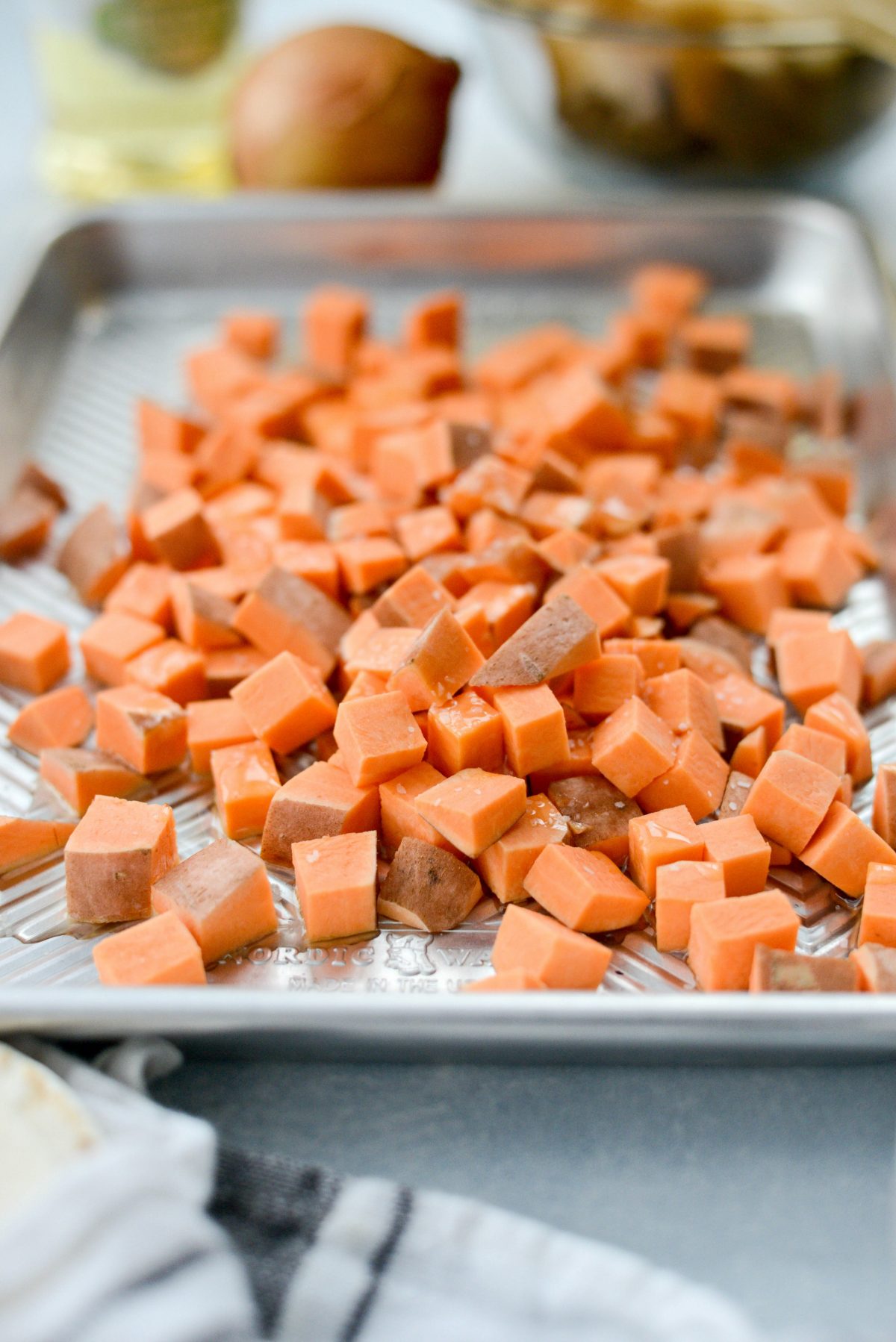 diced raw sweet potatoes on a rimmed sheet pan.