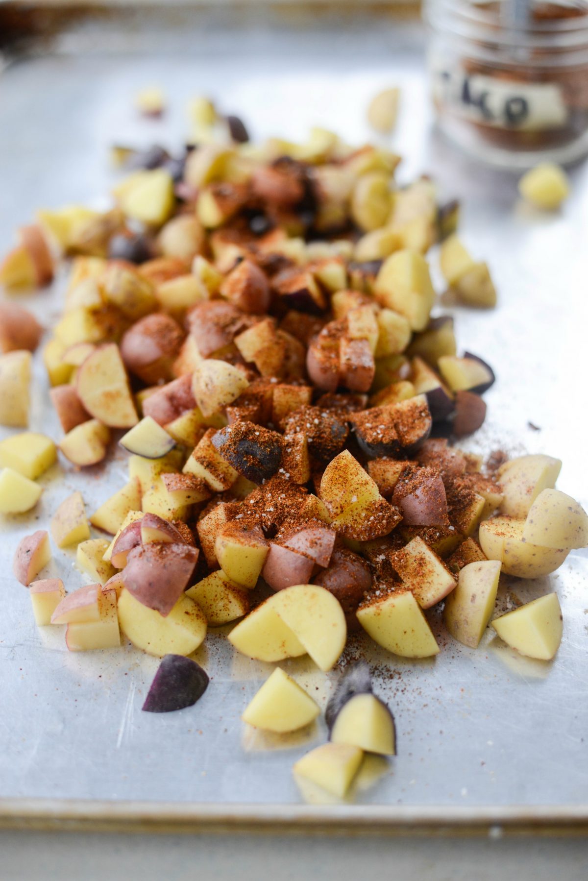 potatoes and seasoning on a sheet pan
