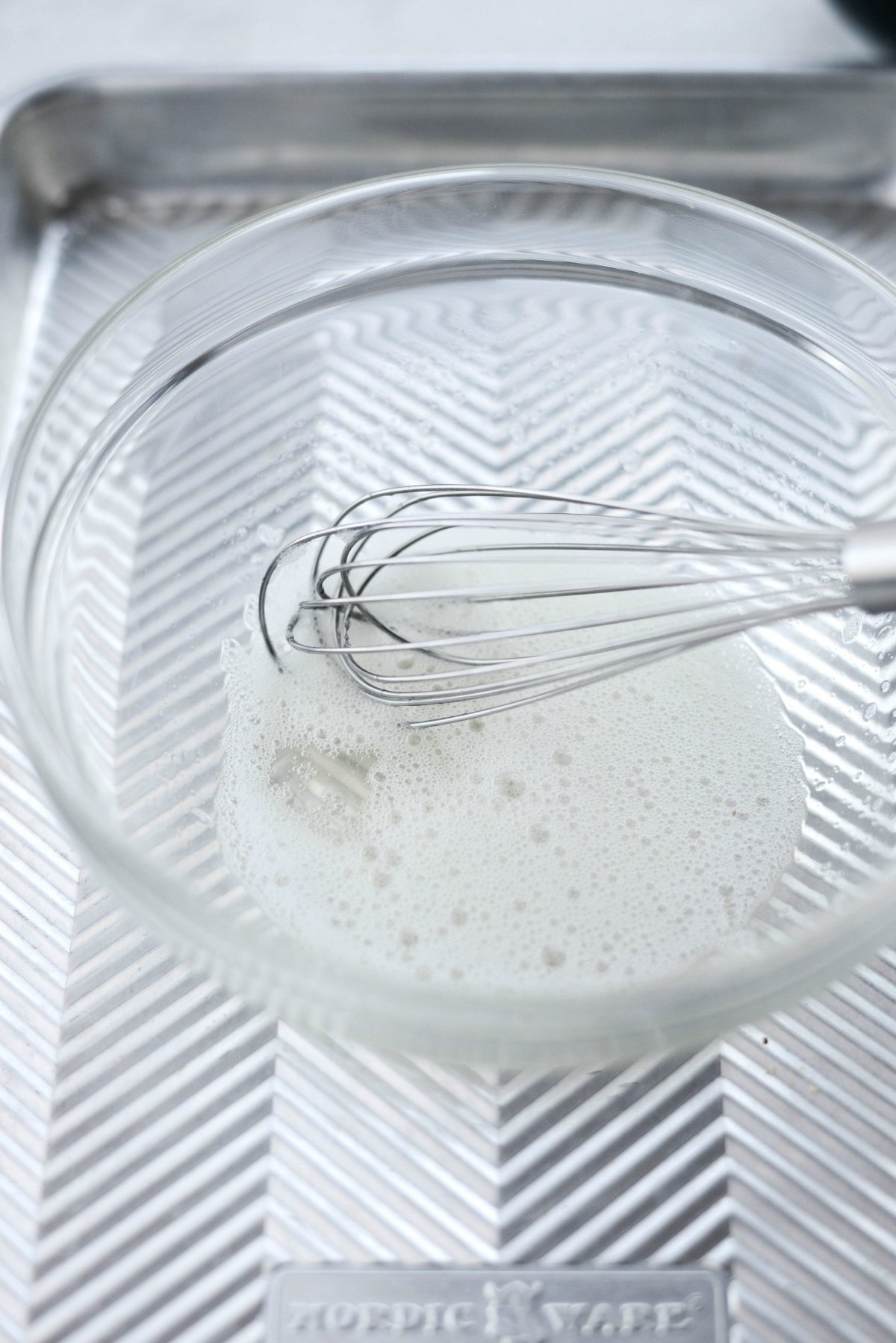 egg whites in a bowl with whisk