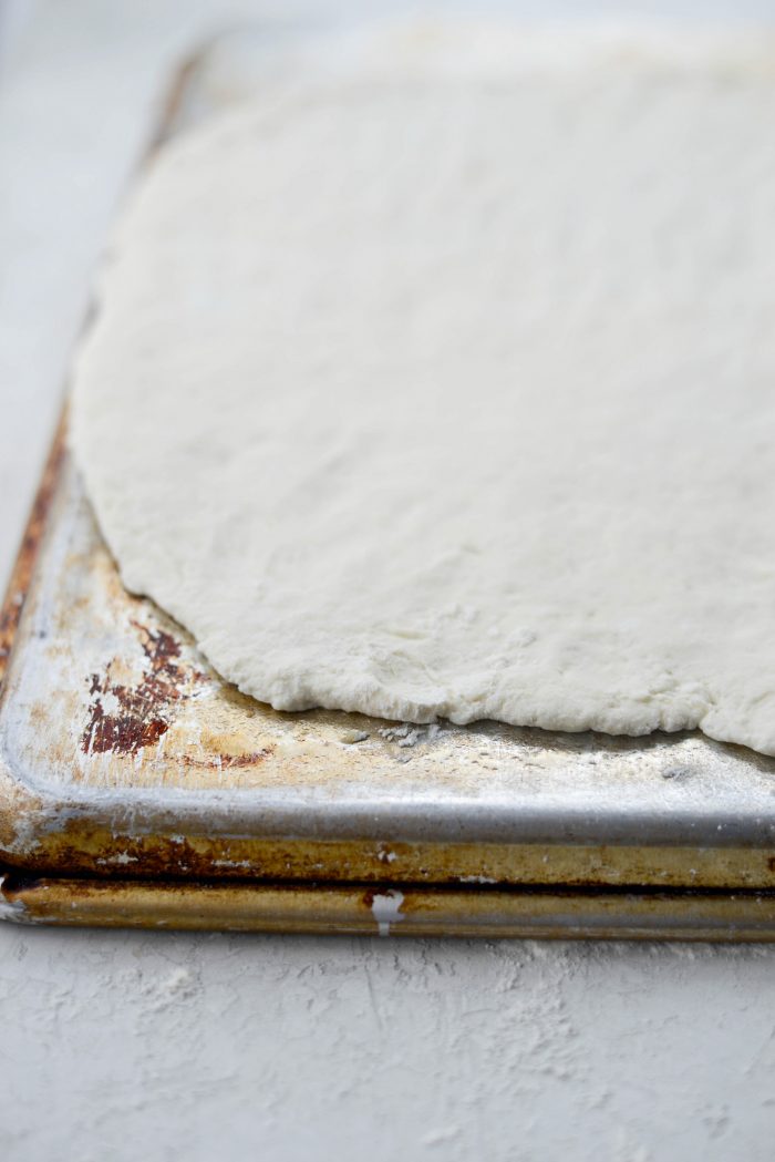 roll out pizza dough and place onto inverted rimmed baking sheet