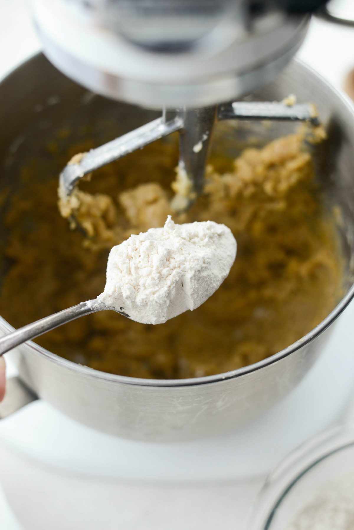 adding spoonfuls of dry ingredients.