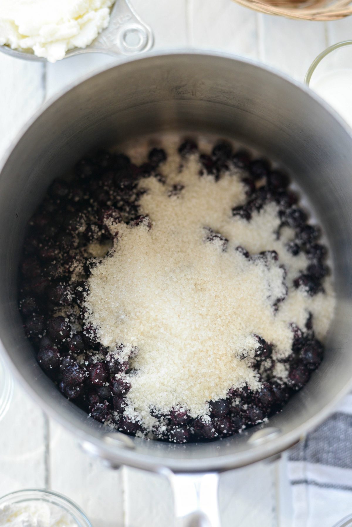 sugar to blueberries in saucepan