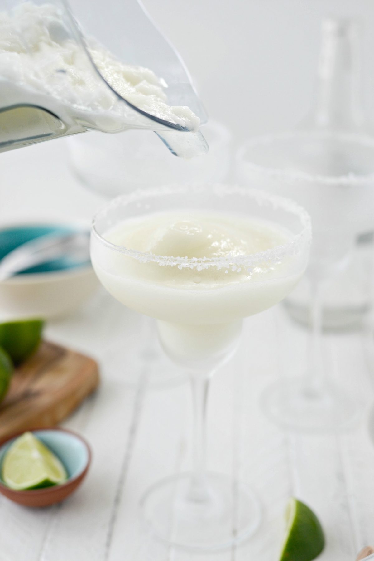 pouring Frozen Margarita Slush into frosted, salt rimmed glasses.