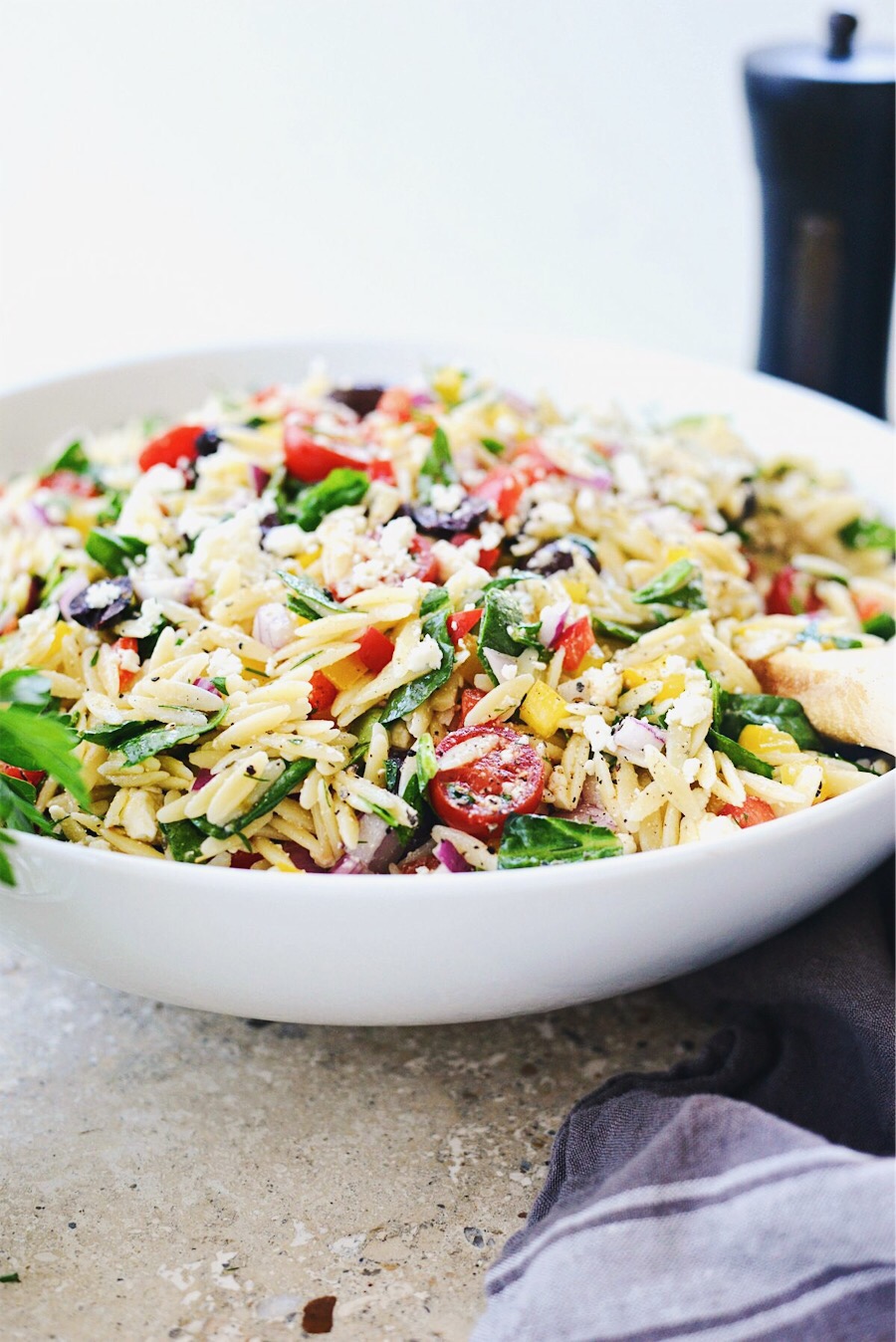 side view of Greek Orzo Salad in white bowl.