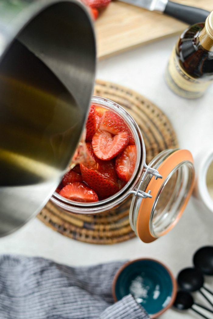 pour the warm pickling liquids over the strawberries