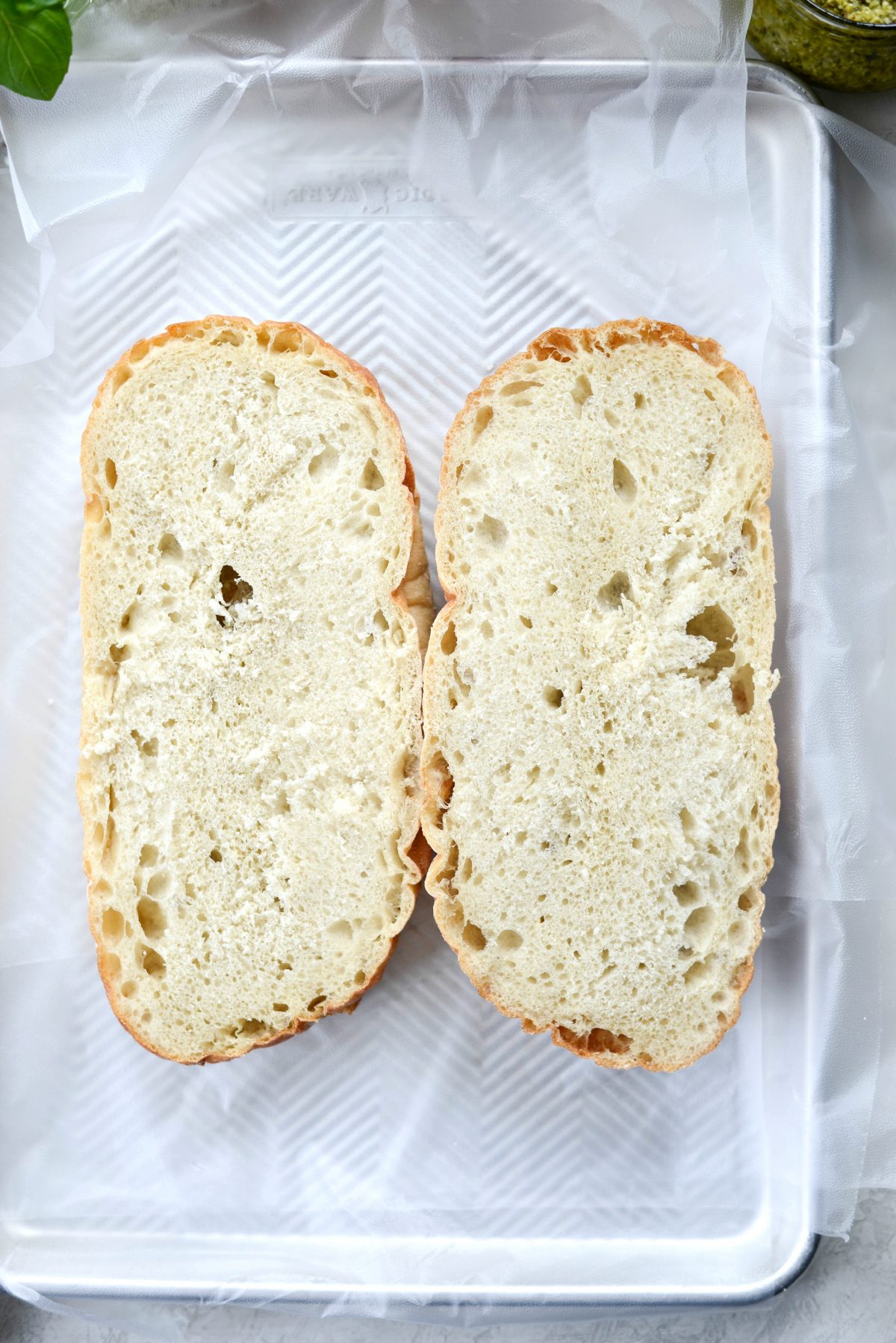 bread halves on plastic wrap set into a rimmed tray