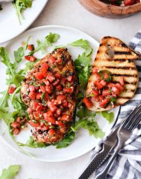 white plate with arugula, grilled chicken bruschetta and grilled bread