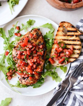 white plate with arugula, grilled chicken bruschetta and grilled bread