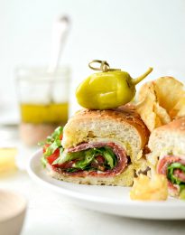 close up of italian sub sandwich with chips and peperoncini
