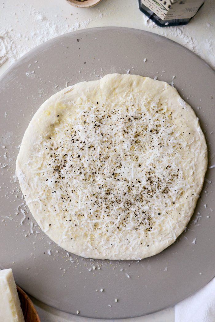 cheeses and black pepper on pizza dough