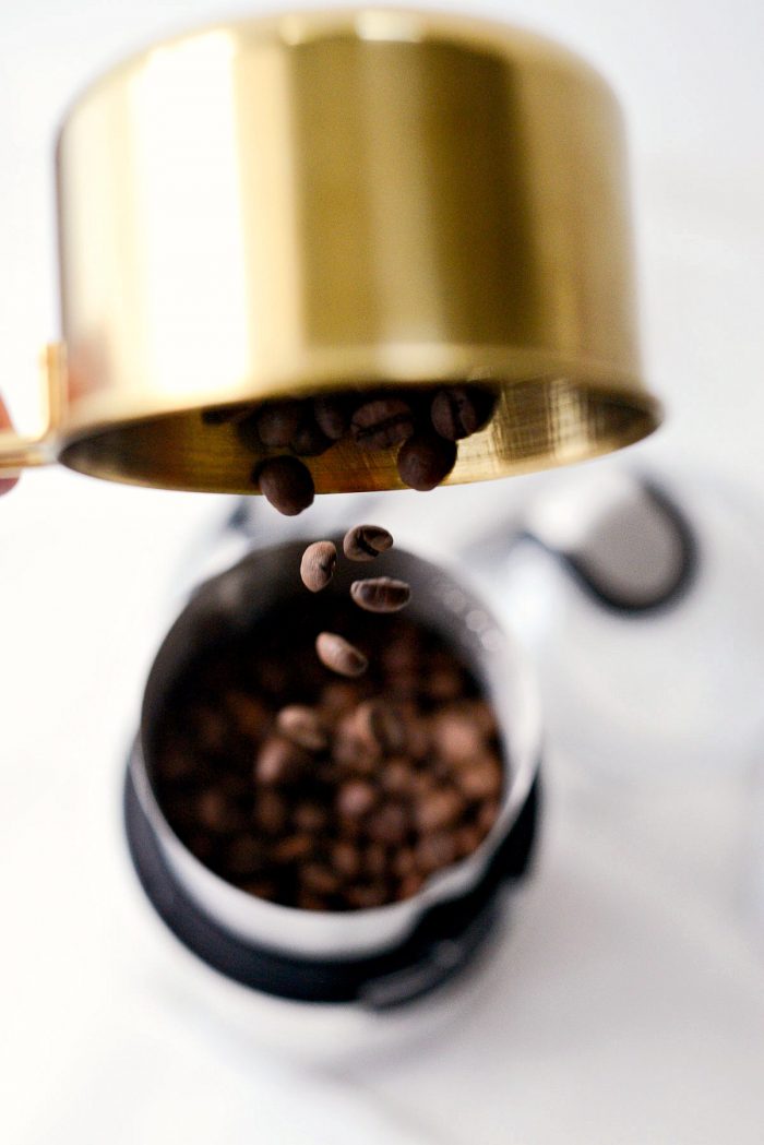 pouring coffee beans into coffee grinder