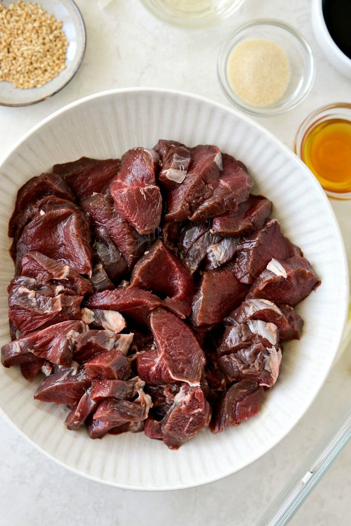 sliced venison backstrap in cream colored bowl