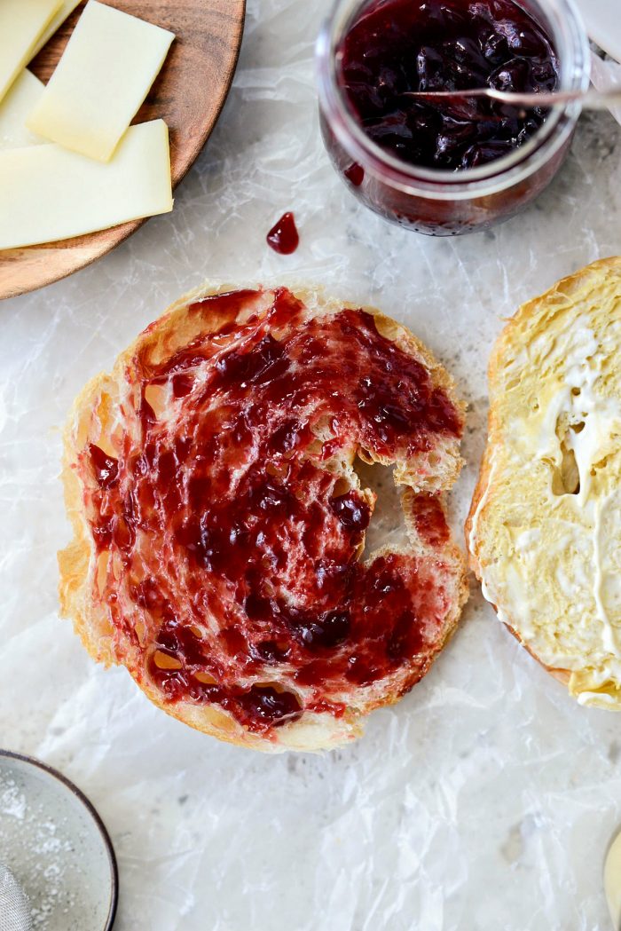 the other croissant half smeared with raspberry jam