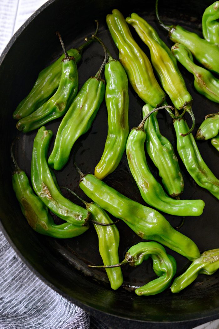 slightly blistered shishito peppers in skillet