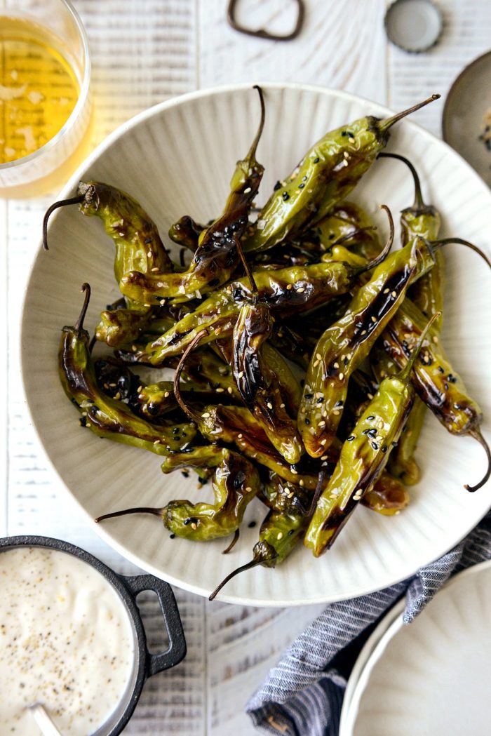 blistered shishito peppers in a cream bowl