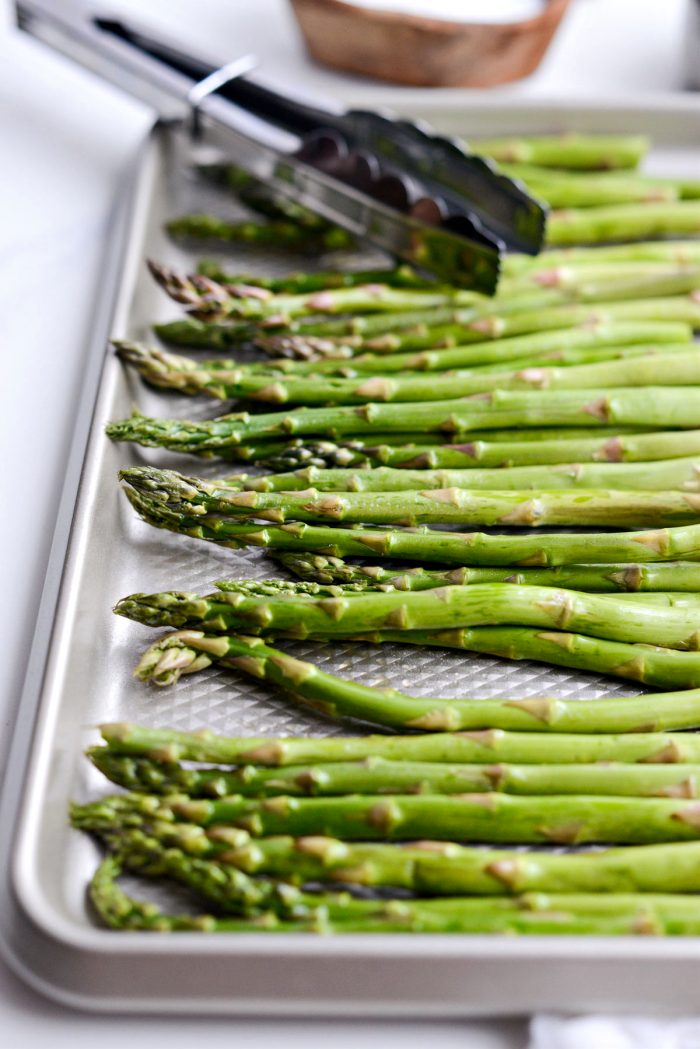 trimmed asparagus in shallow pan coated in olive oil.