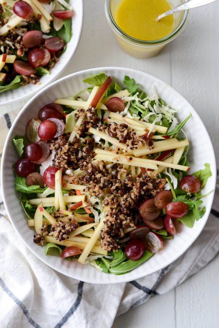 arugula, slaw, apples, grapes and grains in bowl.