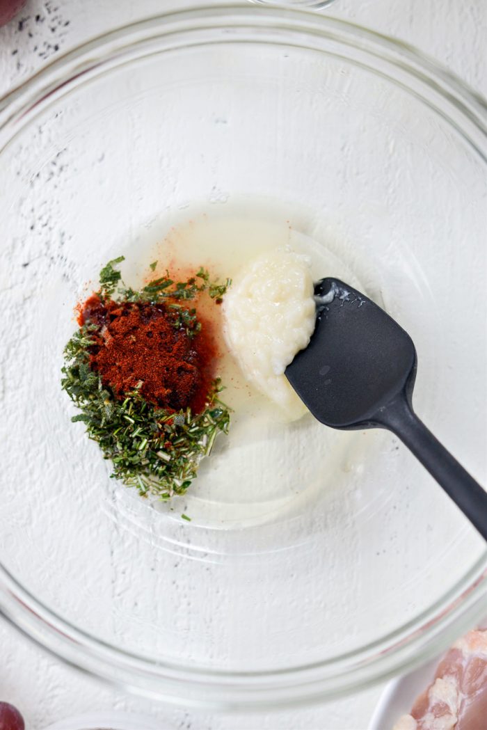 fresh herbs, garlic, paprika, lemon juice and olive oil in a glass bowl.