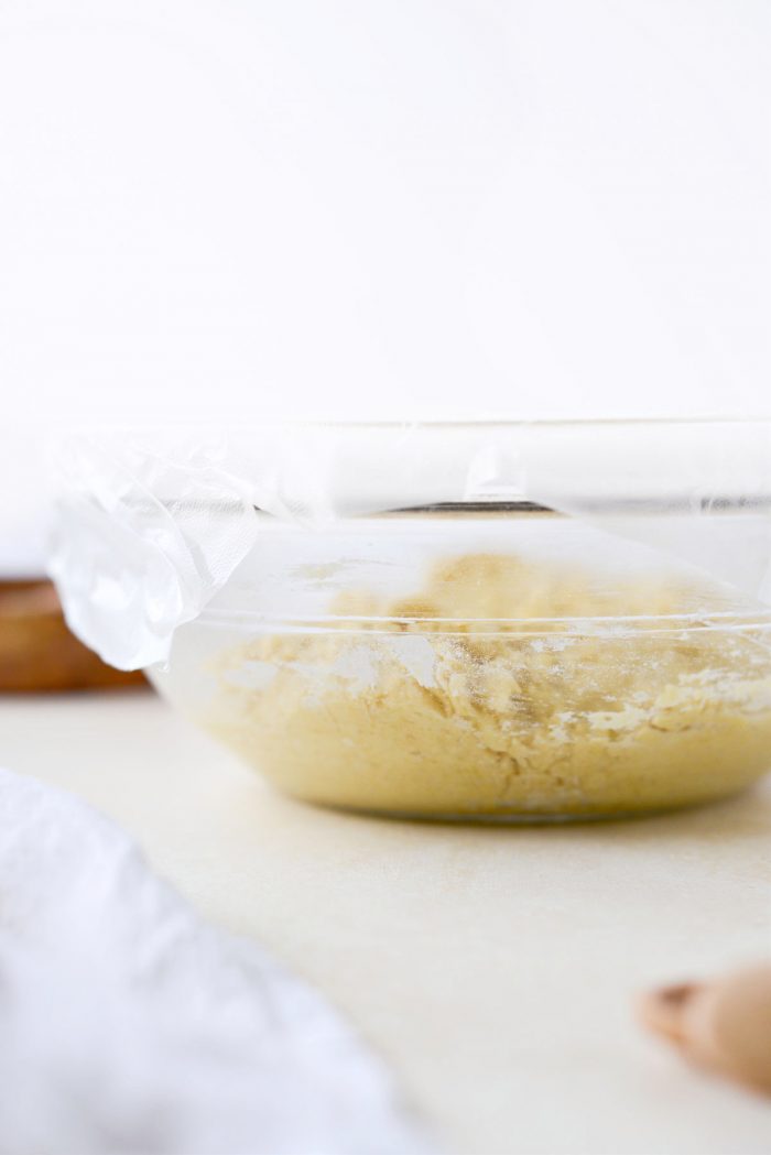 dough in glass bowl covered with plastic wrap to rise.