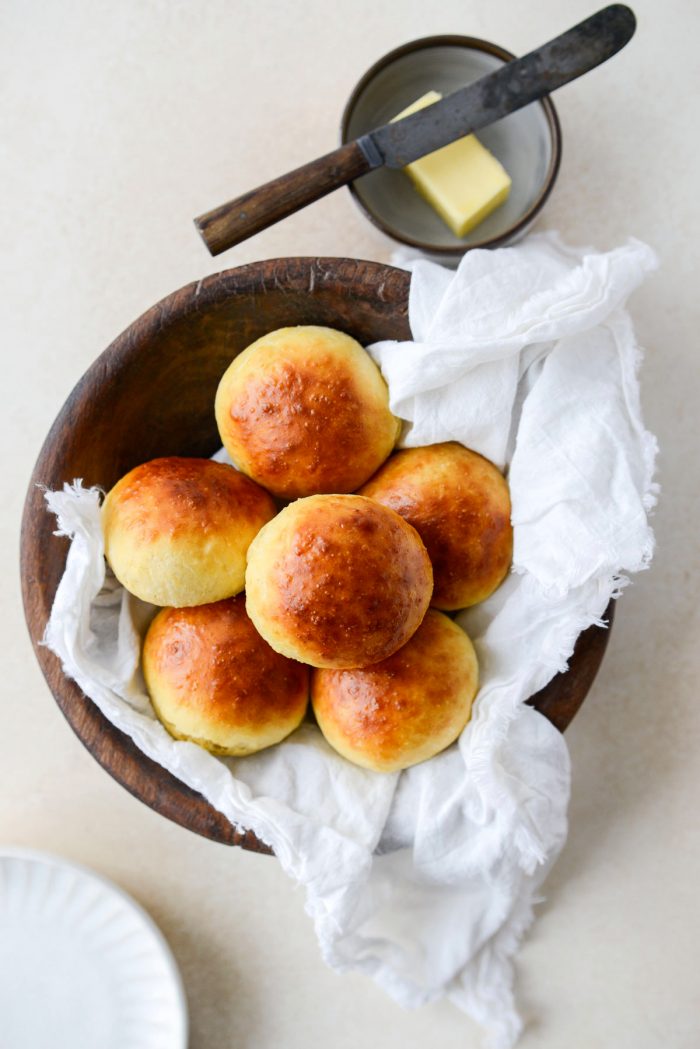 Brioche Dinner Rolls with white frayed linen and dish with butter.