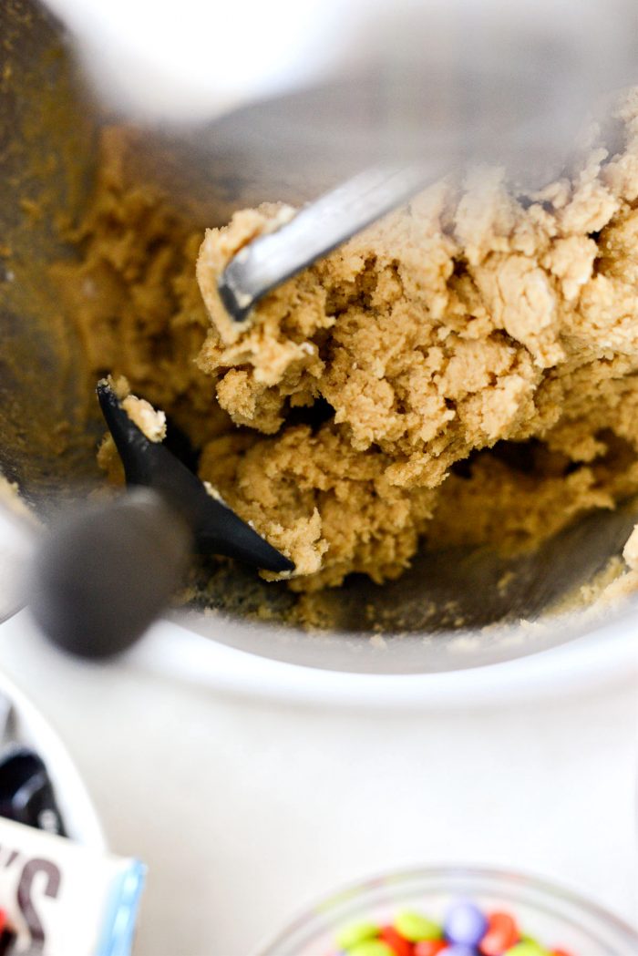 scraping the mixing bowl with a black spatula.