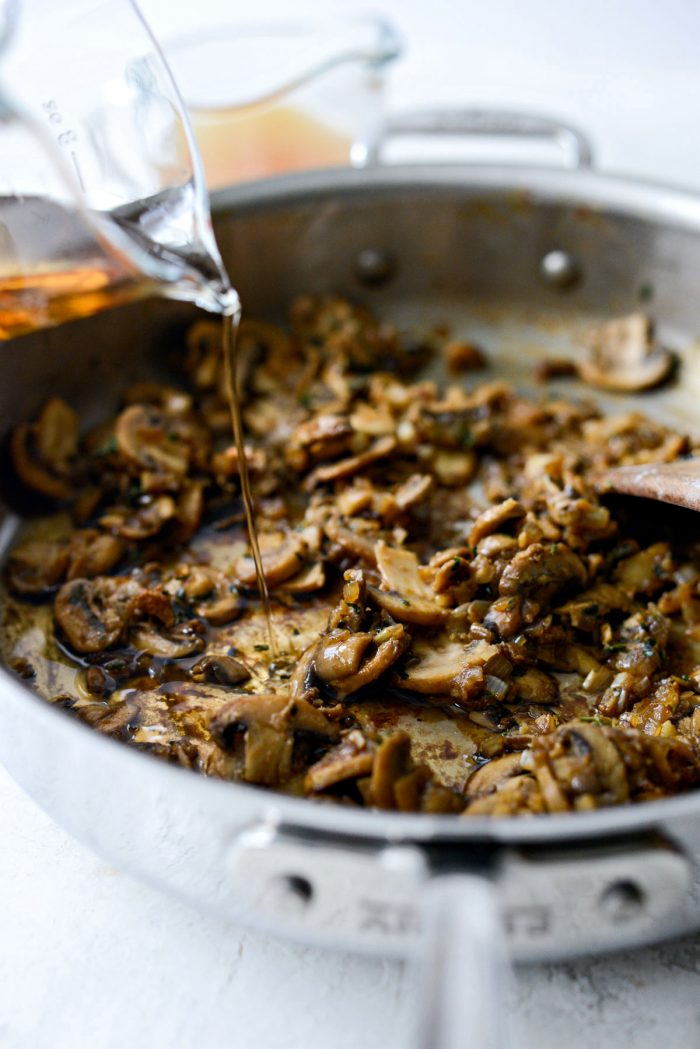 pouring marsala wine into skillet with mushrooms.
