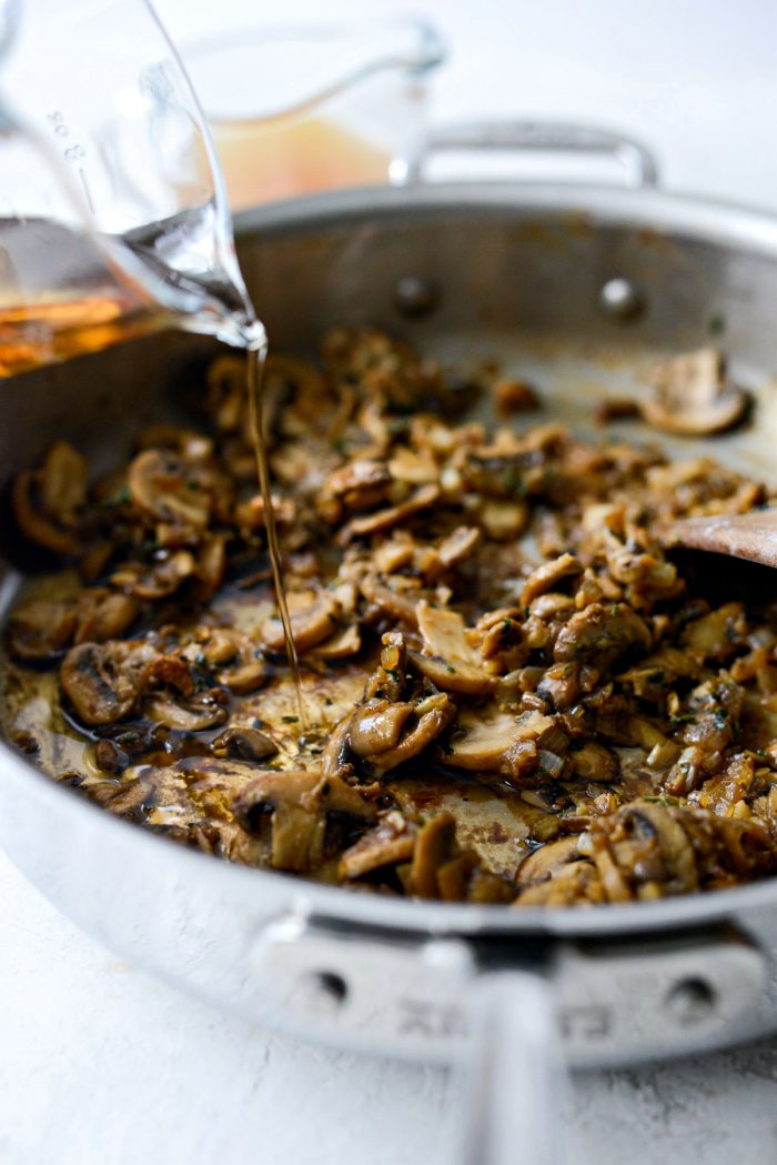 pouring marsala wine into skillet with mushrooms.