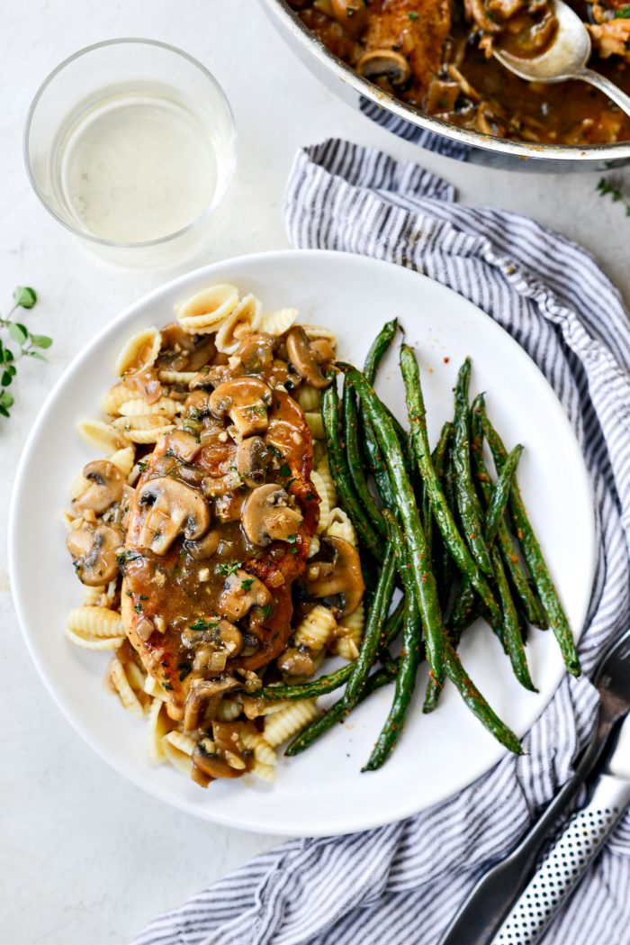 plated lighter chicken marsala on pasta with green beans.