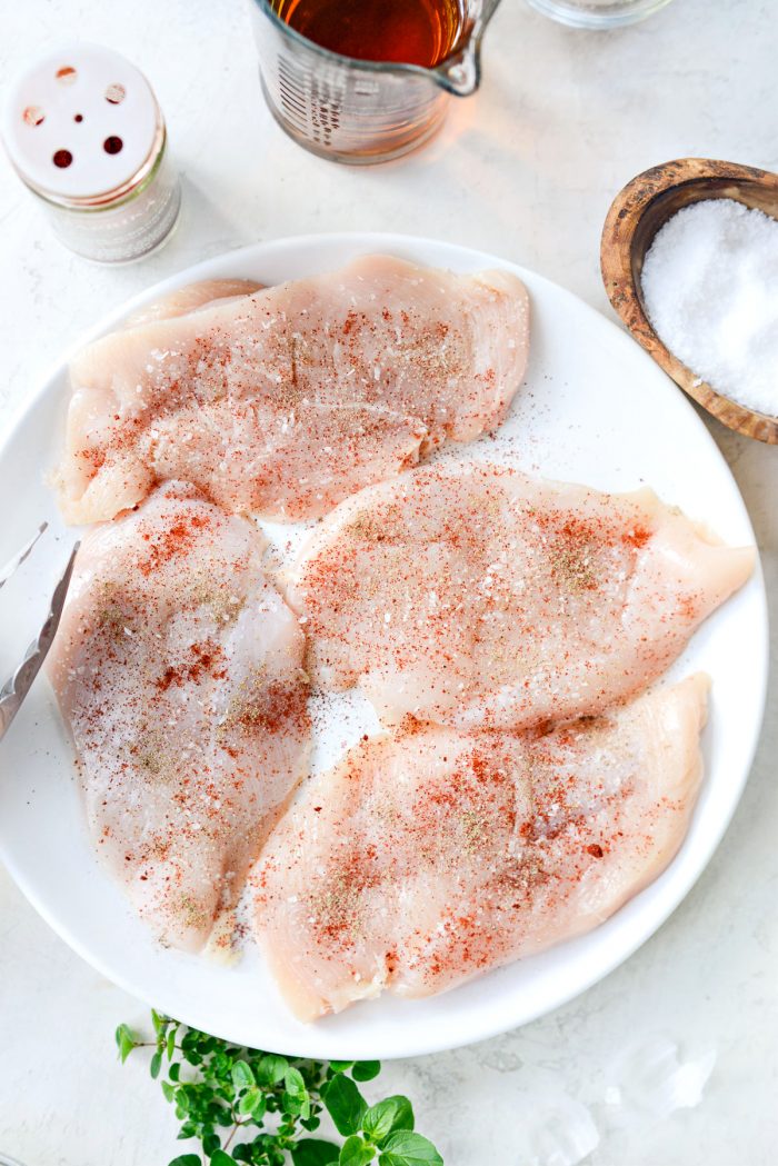 seasoned thin-cut chicken breasts on white plate.