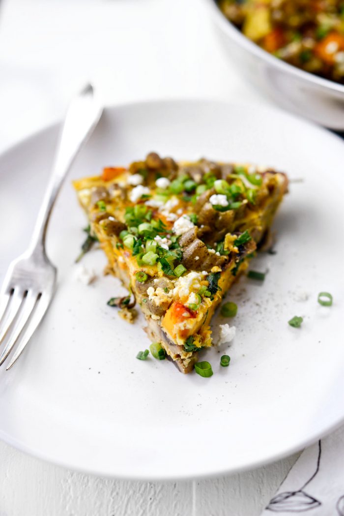 Slice of Roasted Pumpkin Kale and Feta Frittata on white plate.