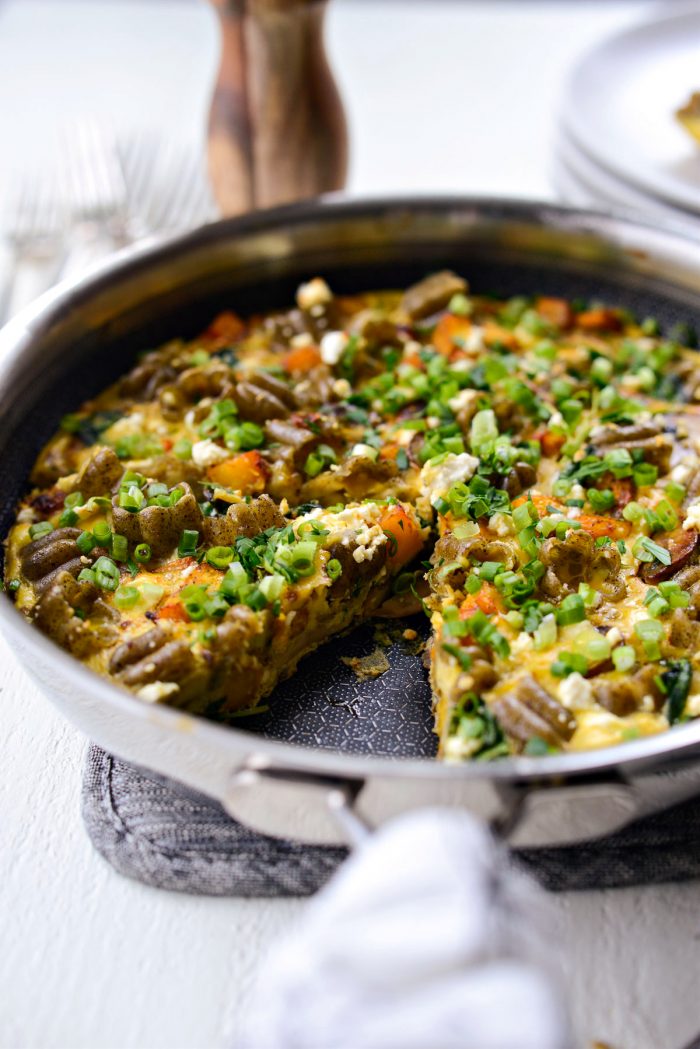 Skillet of Roasted Pumpkin Kale and Feta Frittata with piece missing.