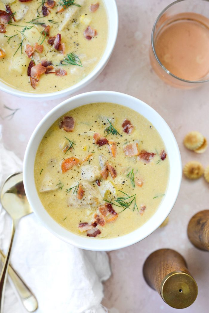 White bowl with salmon chowder and glass of rosé.