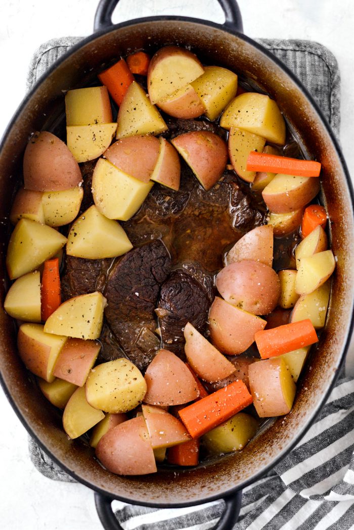 potatoes and carrots with pot roast in dutch oven.