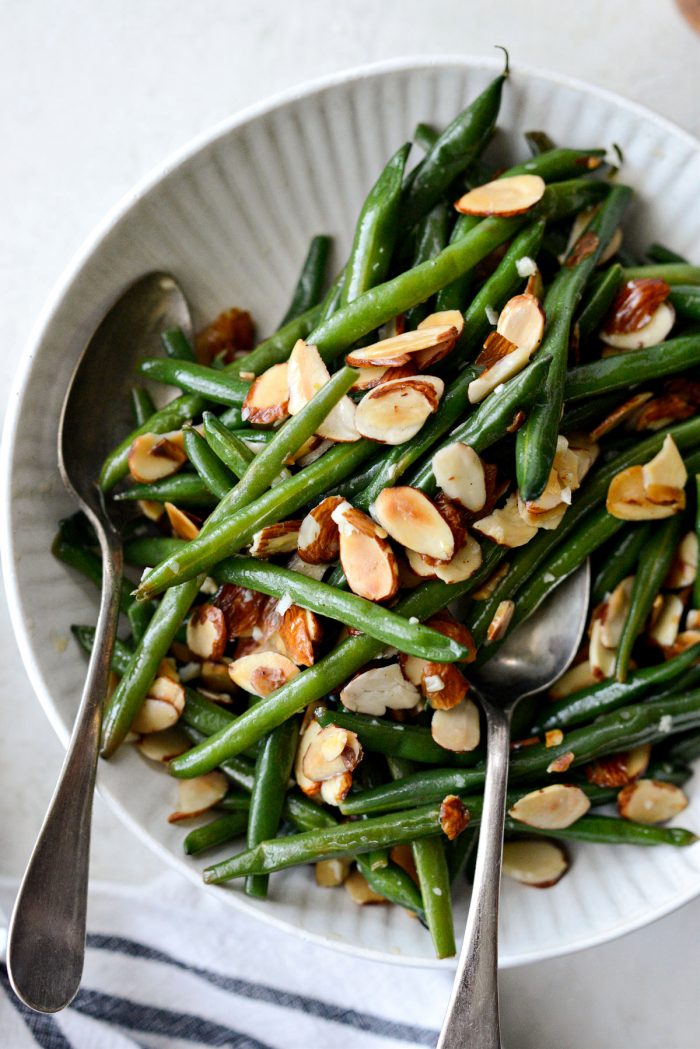 garlicky green beans almondine in cream colored bowl.