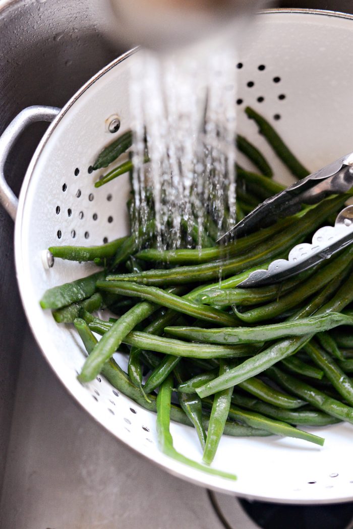 rinsing blanched green beans with cold water.