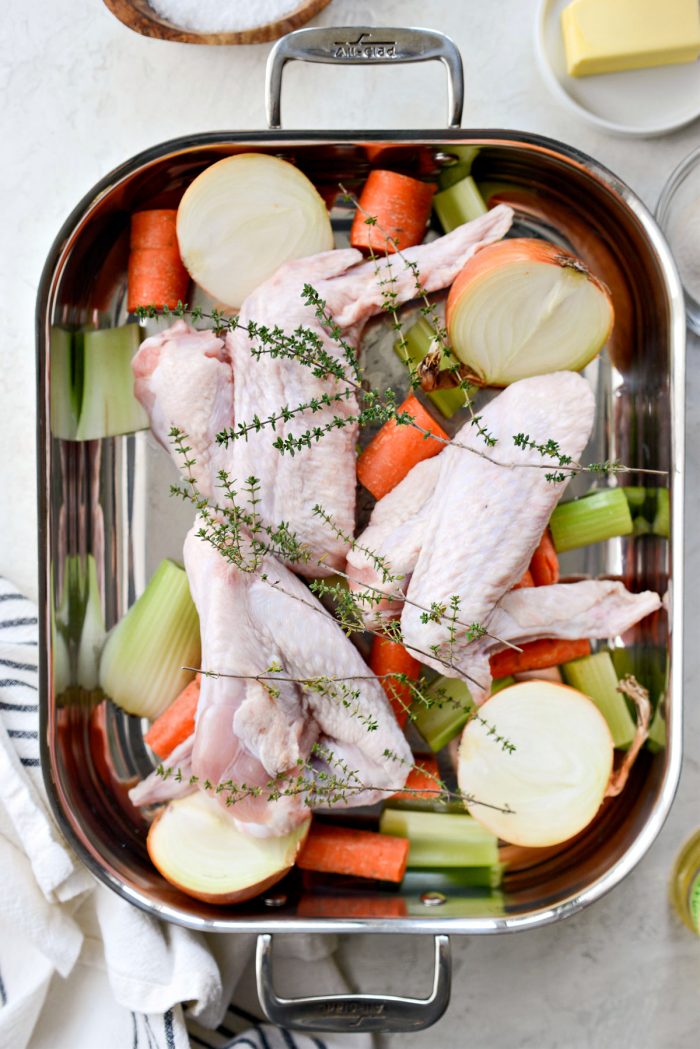 roasting pan with vegetables, herbs and turkey wings.