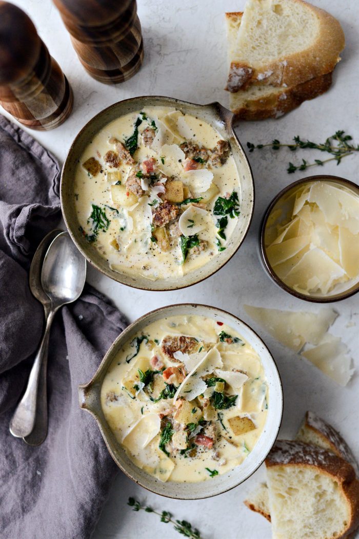 Two bowls of Zuppa Toscana with bread and parmesan cheese.
