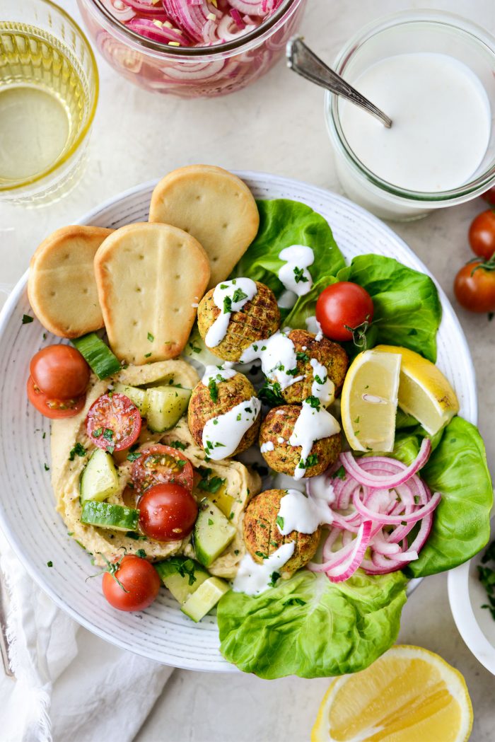 Air Fryer Falafel in a white bowl with pickled red onion and lemon