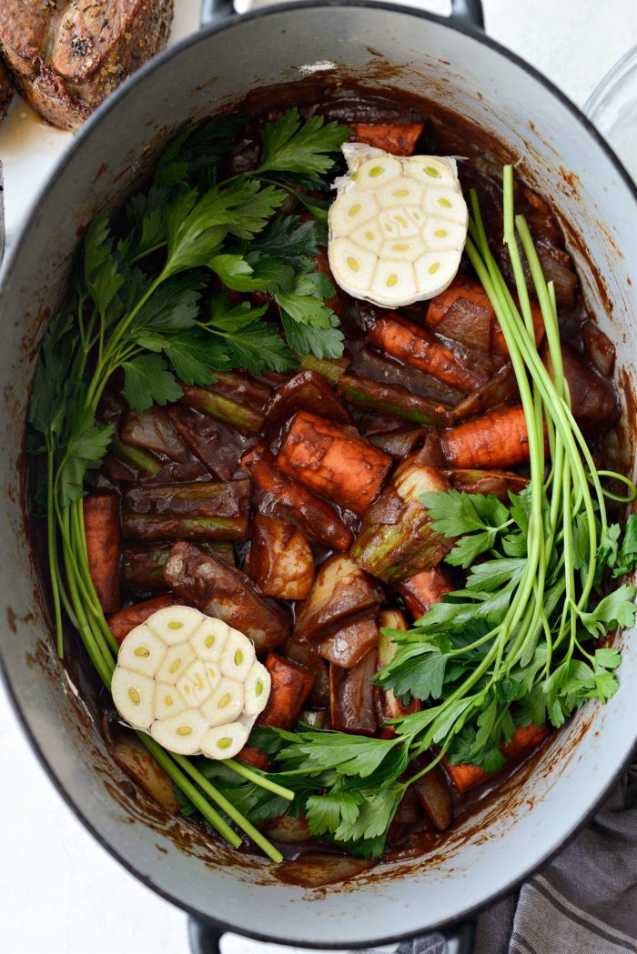 parsley and garlic halves added to vegetables in dutch oven.