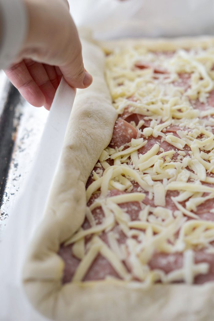 use the parchment to roll the dough towards the 2-inch overhang