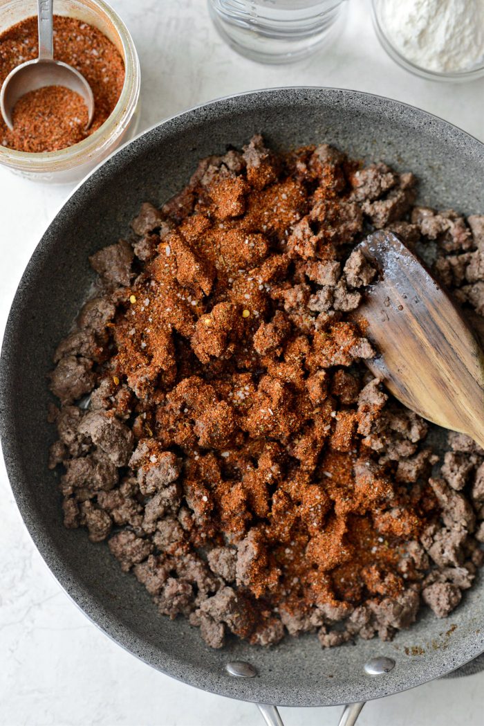 taco seasoning sprinkled over cooked ground beef