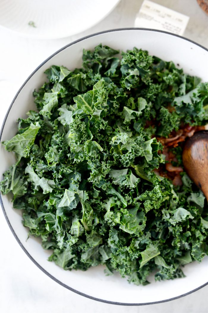 chopped kale added to bacon in skillet